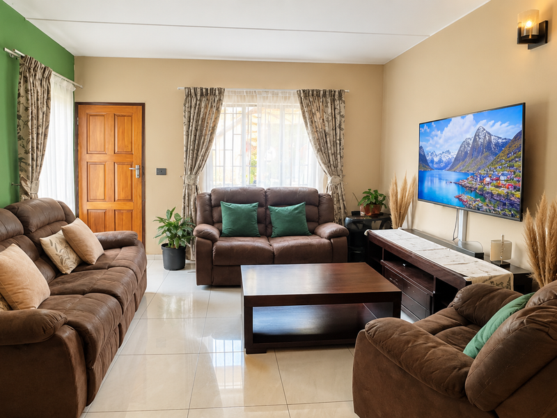 A well-maintained living room featuring polished tile flooring, a feature green wall, and a timber entrance door.