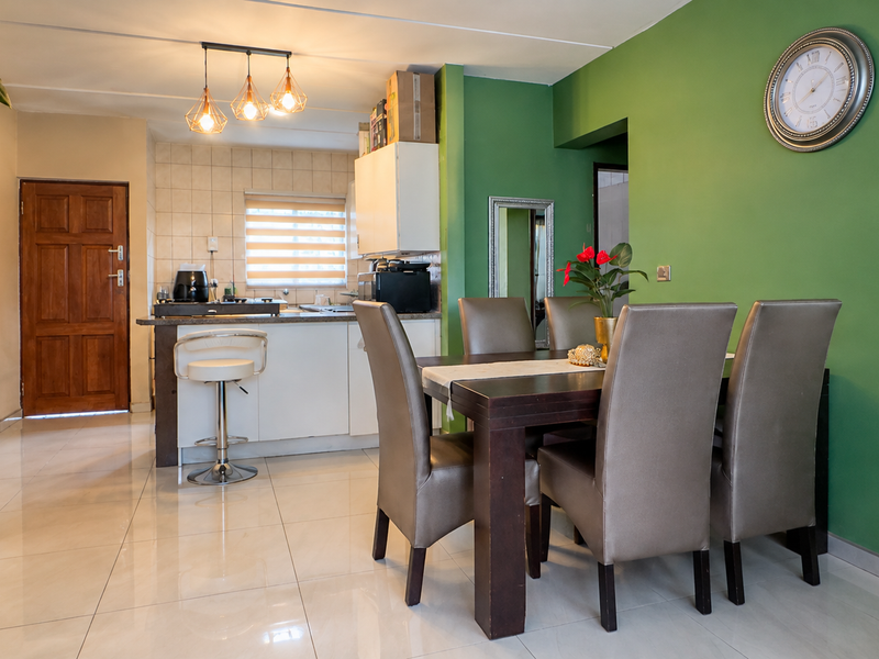Open plan living and dining area featuring tiled flooring, modern pendant lighting, and a functional kitchen space with built-in cabinetry.