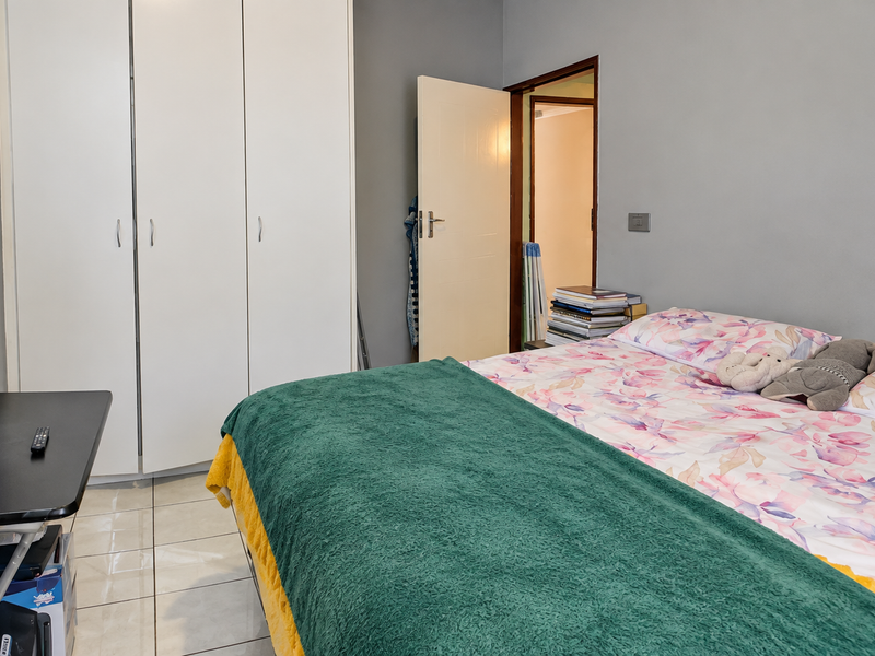 A functional bedroom featuring tiled flooring and a built-in wardrobe, providing essential storage space within the apartment.