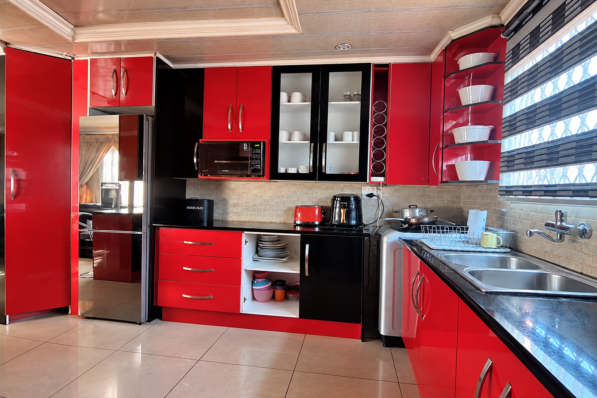 A vibrant kitchen featuring high-gloss red and black cabinetry, a double sink with mixer tap, tiled backsplash, and integrated microwave.