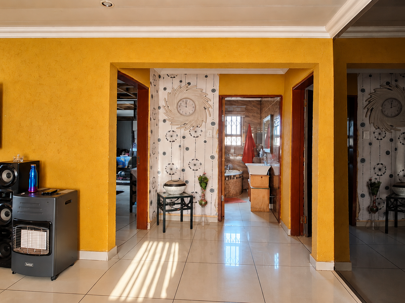 A bright hallway featuring yellow textured walls, tiled flooring, and a mirrored sliding door, providing access to adjacent living and bathroom areas.