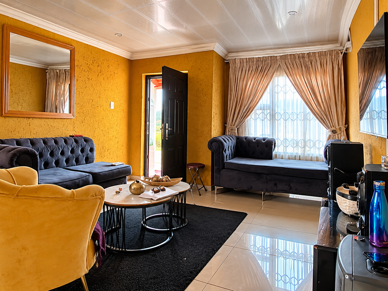 A vibrant living room featuring textured yellow walls, tiled flooring, recessed ceiling lights, and secure window treatments.