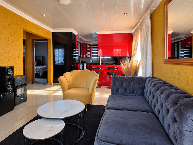 Open-plan living area featuring a vibrant red kitchen with breakfast bar, tiled flooring, and distinctive textured yellow walls.