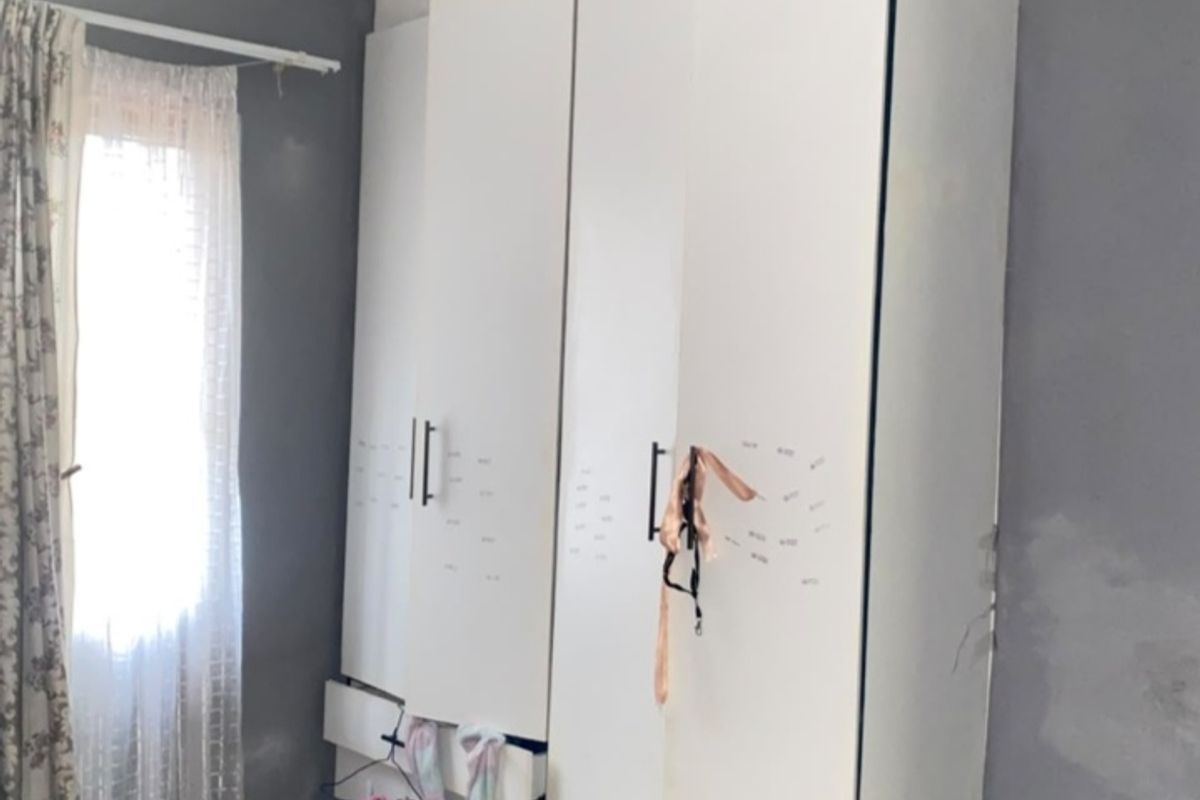 Bedroom featuring a built-in wardrobe, tiled flooring, and decorative cornice. The room requires maintenance to address ceiling staining and wall finish repairs.