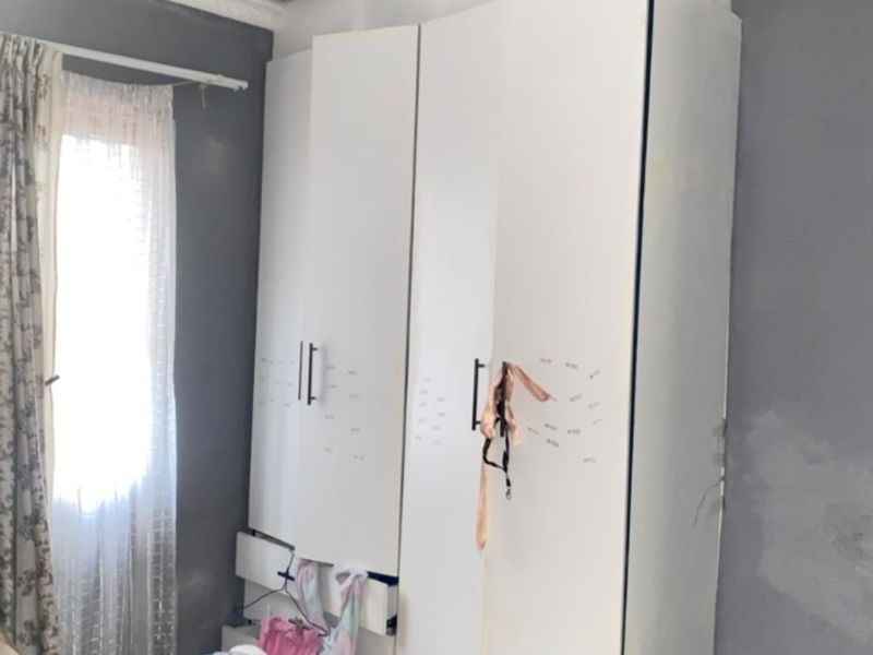 Bedroom featuring a built-in wardrobe, tiled flooring, and decorative cornice. The room requires maintenance to address ceiling staining and wall finish repairs.