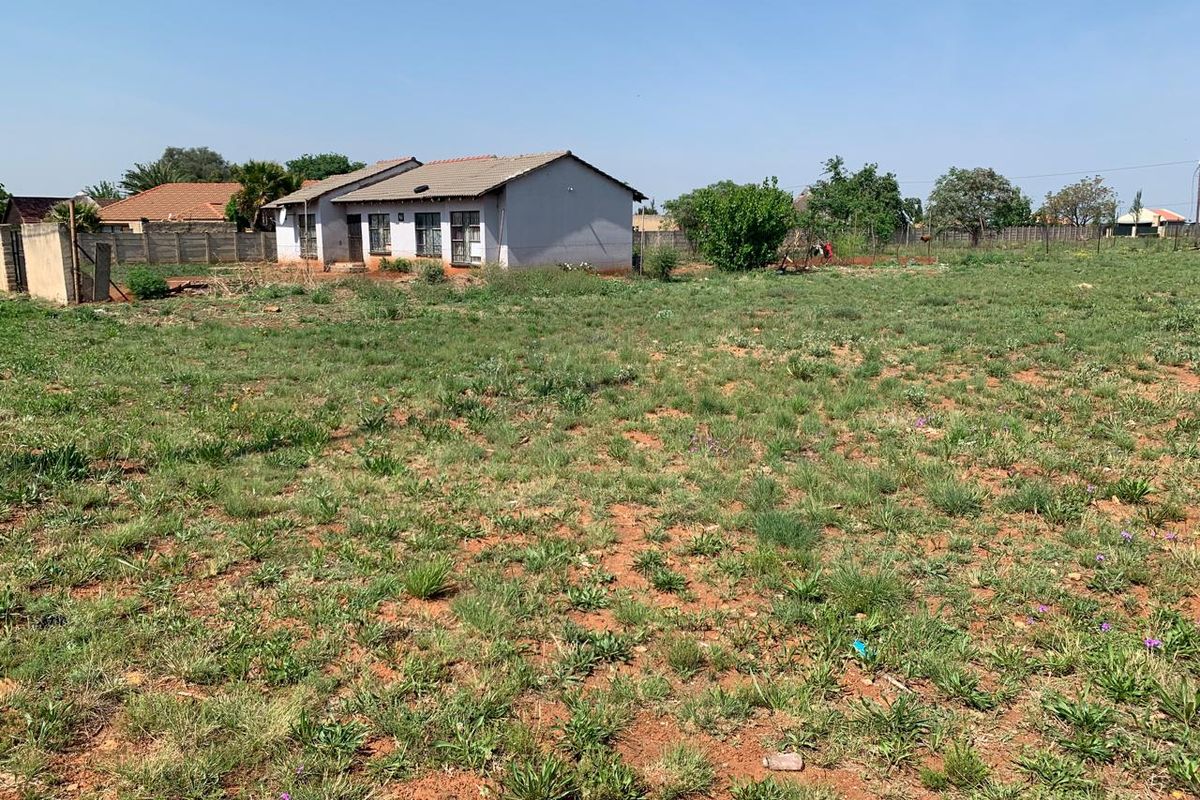 A view of a residential plot featuring a single-story dwelling with a tiled roof and surrounding perimeter boundary walls.