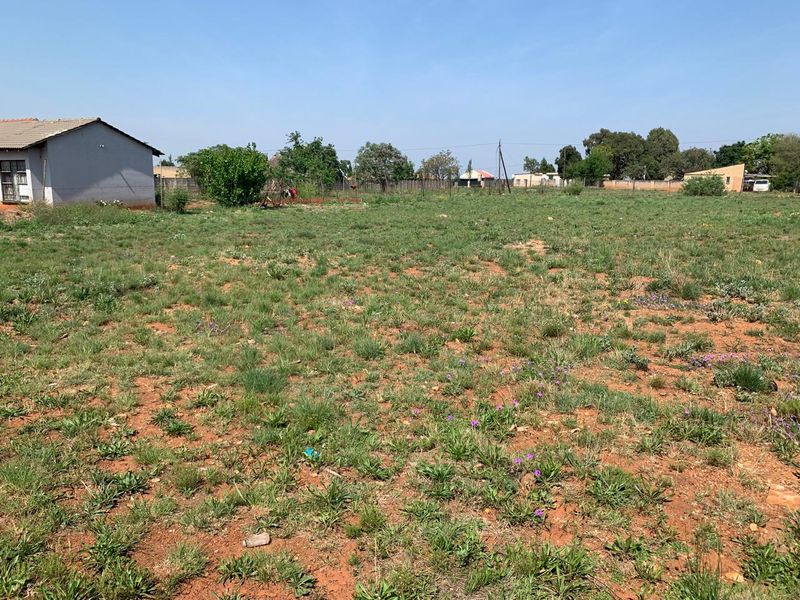 A view of a vacant residential plot featuring natural grassland and perimeter fencing, offering a blank canvas for future development.