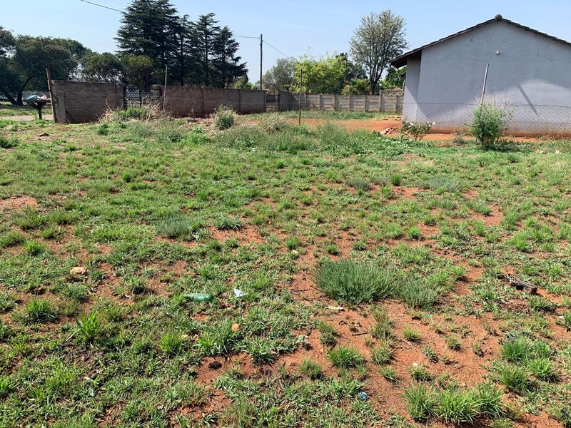 A view of the rear yard area featuring unimproved land, perimeter brick walling, and wire fencing.