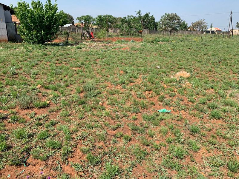 A view of the vacant residential land featuring natural grass cover and perimeter boundary fencing.