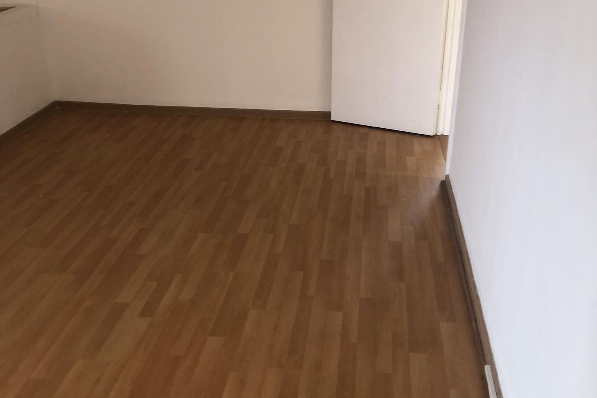 An empty bedroom featuring laminate flooring and neutral walls, providing a blank canvas for personalization.