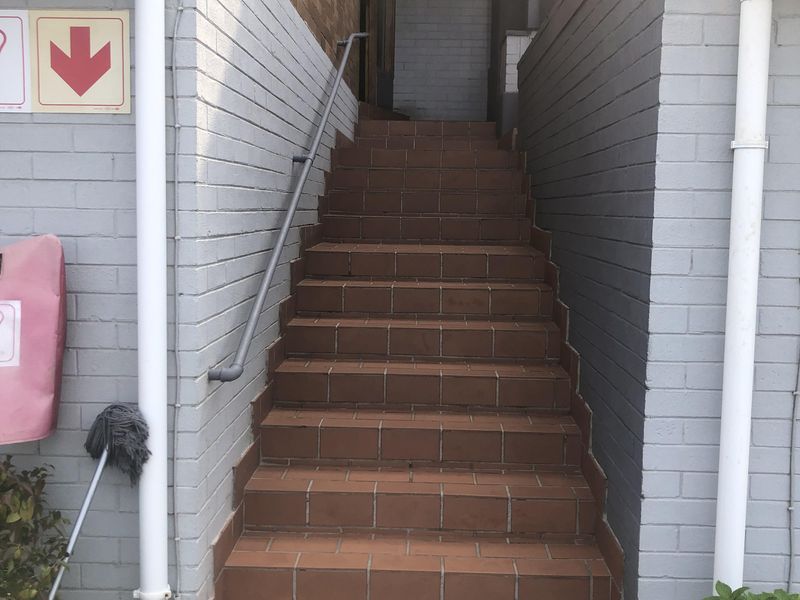 An exterior staircase with tiled steps and a metal handrail leading to an entrance.