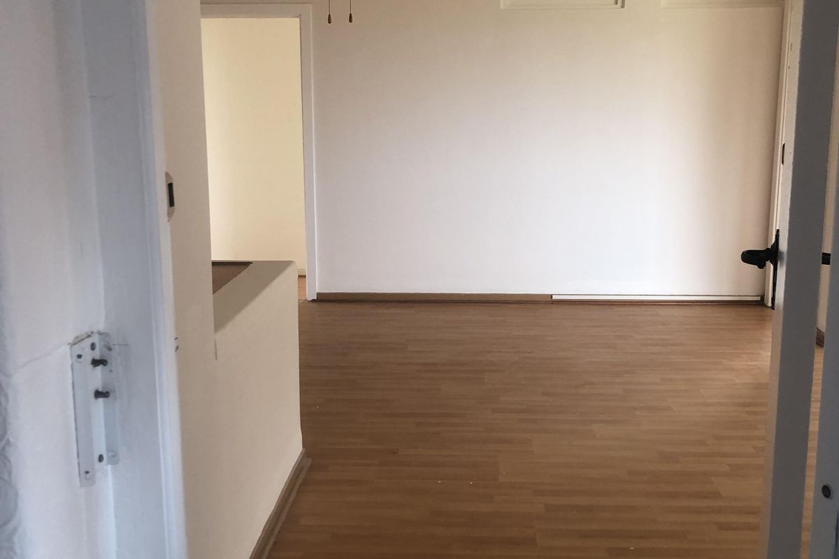 An empty living room featuring laminate flooring and a ceiling fan, offering a blank canvas for interior design and personalization.