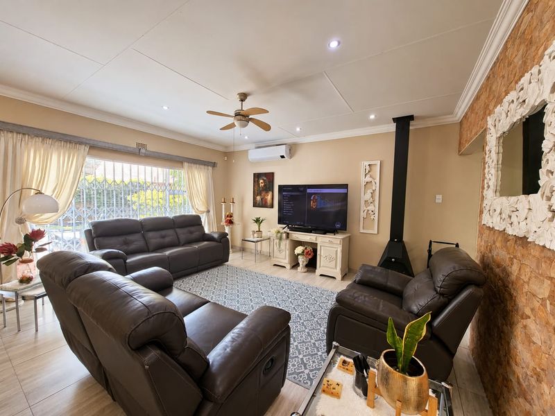 A comfortable living room featuring a stone accent wall, a modern freestanding fireplace, split-system air conditioning, and tiled flooring.