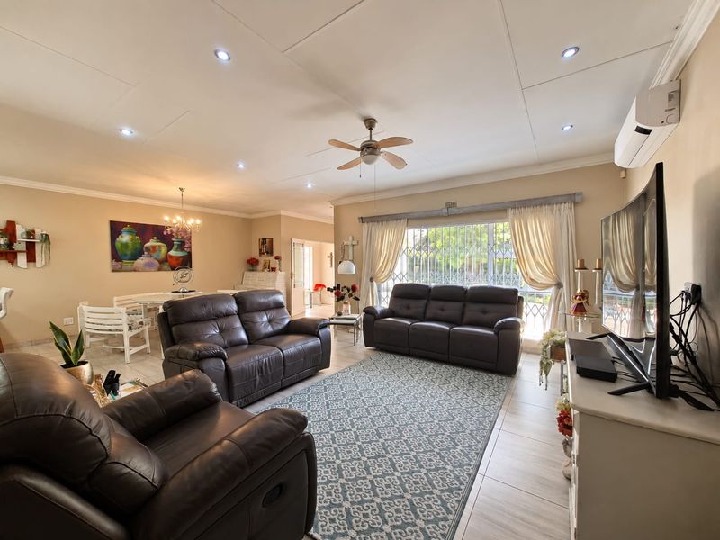 Spacious open-plan living and dining area featuring tiled floors, recessed lighting, a ceiling fan, and a wall-mounted air conditioning unit.