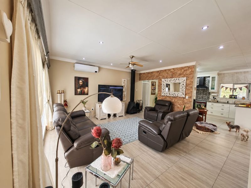 Spacious open-plan living area featuring tiled floors, a stone-cladding feature wall, a fireplace, and a modern kitchen with built-in cabinetry.