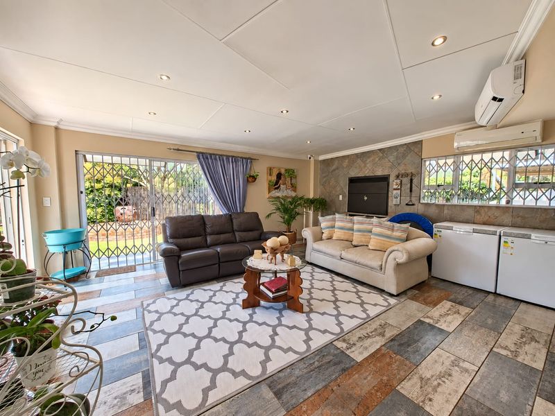 Spacious living room featuring a stone-clad fireplace, tiled flooring, recessed lighting, and dual air conditioning units, with direct access to the outdoor area.