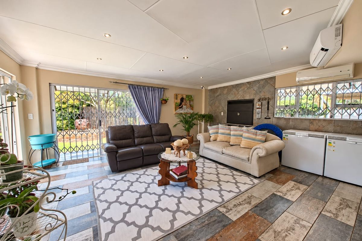 Spacious living room featuring a stone-clad fireplace, tiled flooring, recessed lighting, and dual air conditioning units, with direct access to the outdoor area.