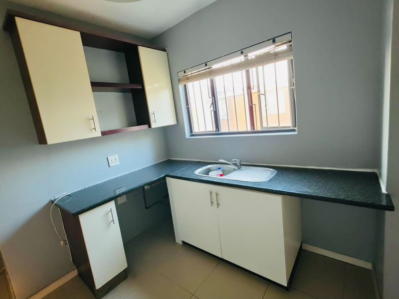 A clean and functional kitchen featuring built-in cabinetry, granite countertops, a stainless steel sink, and tiled flooring.
