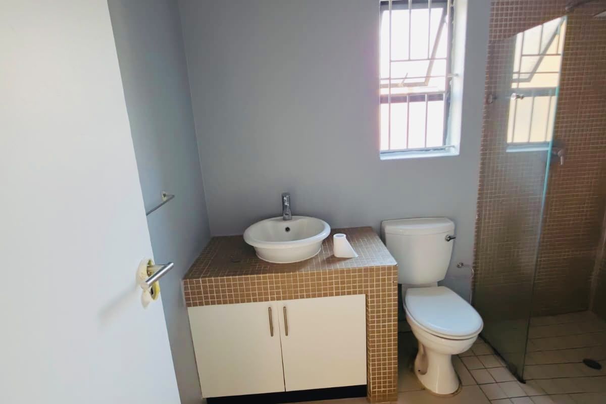 A functional bathroom featuring a tiled vanity with a vessel sink, a toilet, a separate shower enclosure, and a bathtub.