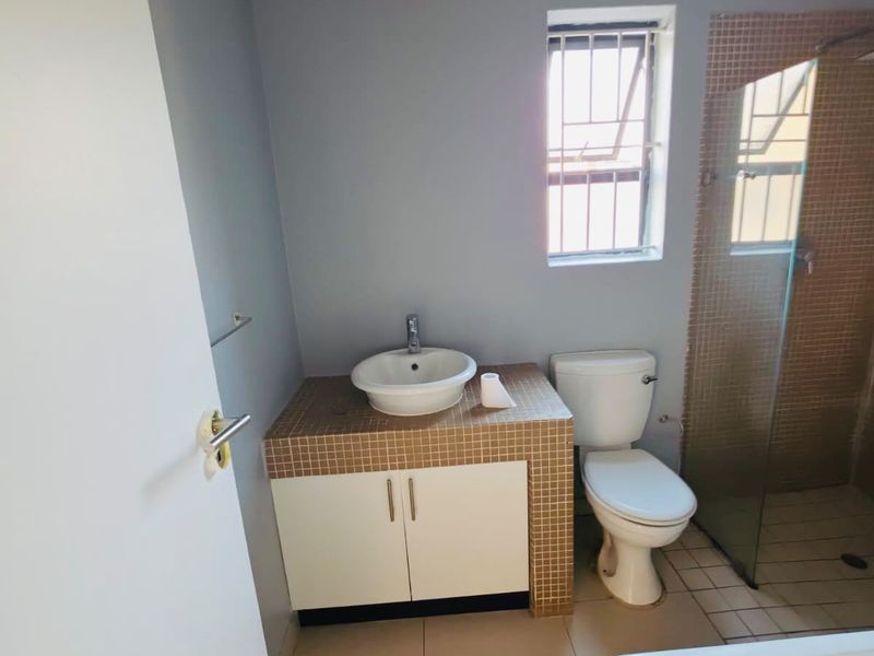 A functional bathroom featuring a tiled vanity with a vessel sink, a toilet, a separate shower enclosure, and a bathtub.