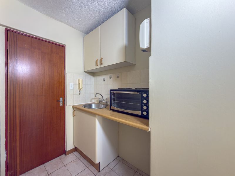 Compact scullery area featuring built-in cabinetry, a stainless steel sink, and tiled backsplash, providing functional utility space.