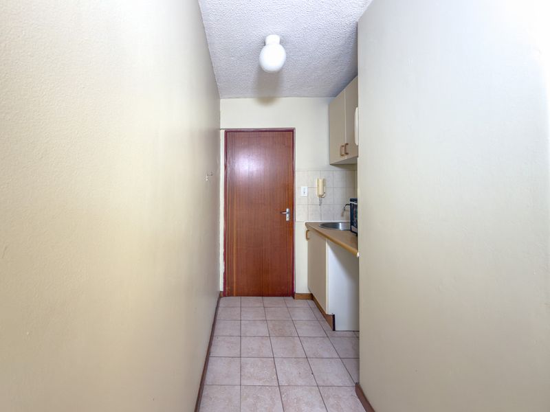 A compact kitchenette featuring basic built-in cabinetry, a stainless steel sink, and tiled flooring, presenting an opportunity for modernization and renovation.