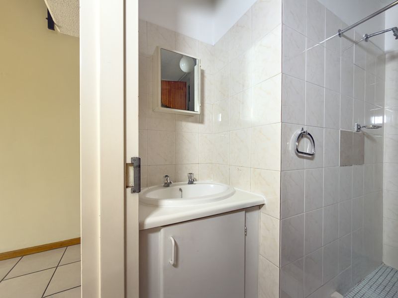 A compact bathroom featuring a vanity cabinet with a basin, wall-mounted medicine cabinet, and a tiled shower area.