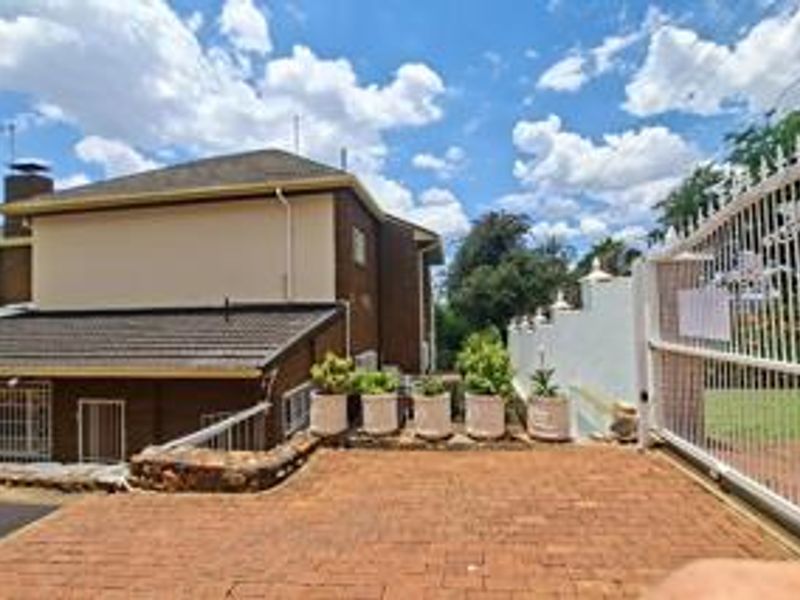 Front exterior view of the property featuring a brick driveway, security gate, and tiled roof structure.