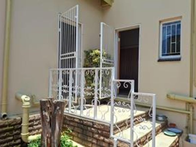 Rear exterior view of the property featuring brick steps, wrought iron security gates, and railings with visible exterior plumbing.