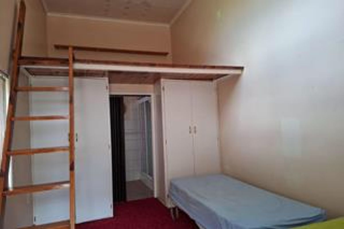 Bedroom featuring a mezzanine loft level with a wooden ladder and built-in cupboards, offering additional vertical space and storage potential.