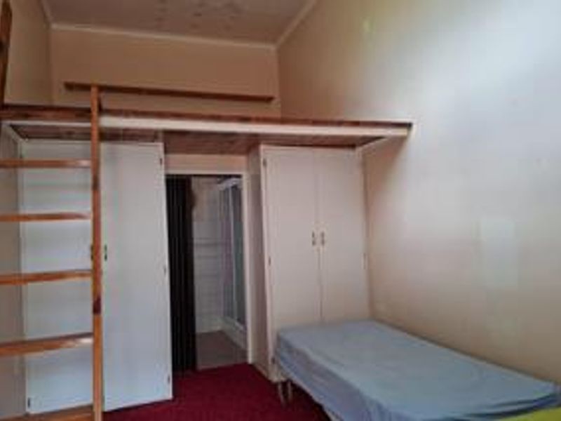 Bedroom featuring a mezzanine loft level with a wooden ladder and built-in cupboards, offering additional vertical space and storage potential.