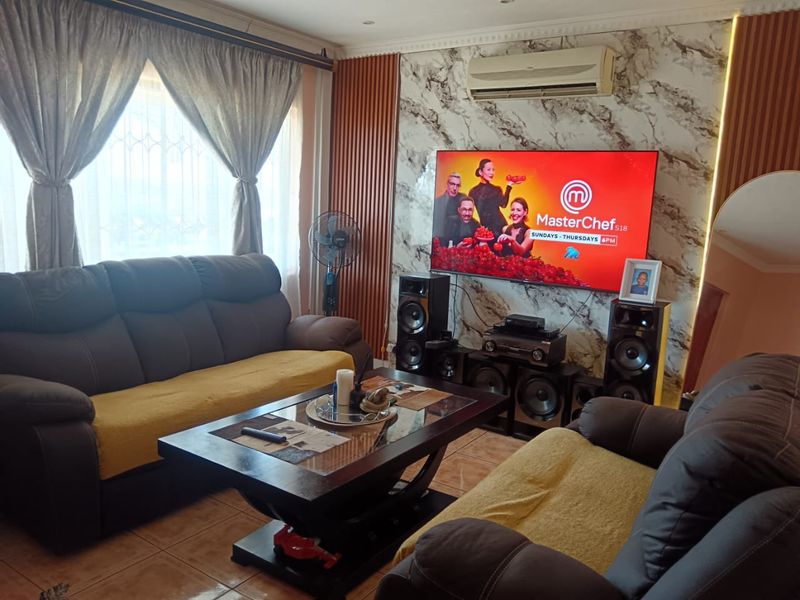 A comfortable living room featuring a marble-effect feature wall with vertical timber accents, tiled flooring, and a wall-mounted air conditioning unit.