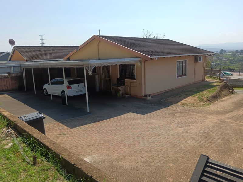 Front exterior view of a single-story house featuring a paved driveway, attached carport, and tiled roof structure.