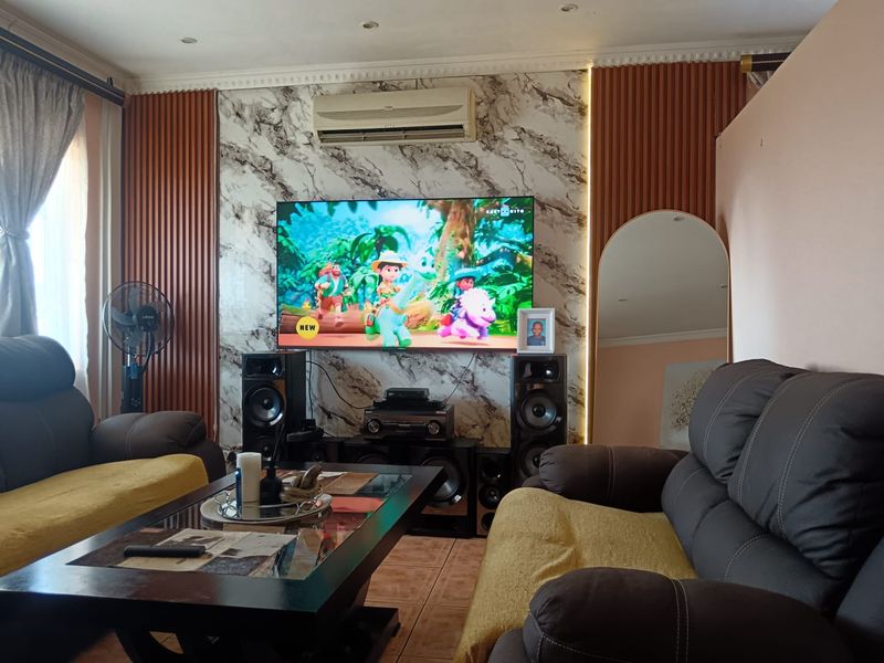 A comfortable living room featuring a marble-effect feature wall with decorative wood paneling, recessed lighting, and a wall-mounted air conditioning unit.