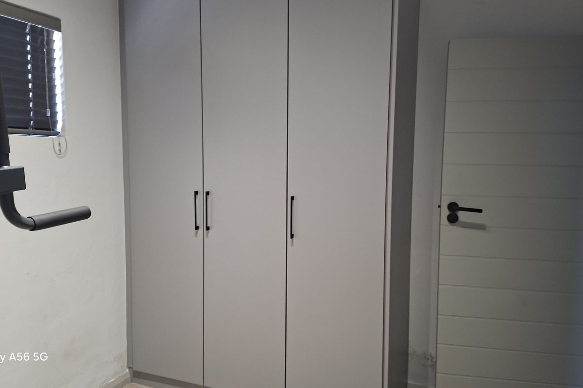 A clean bedroom featuring modern built-in cupboards and a neutral interior door.