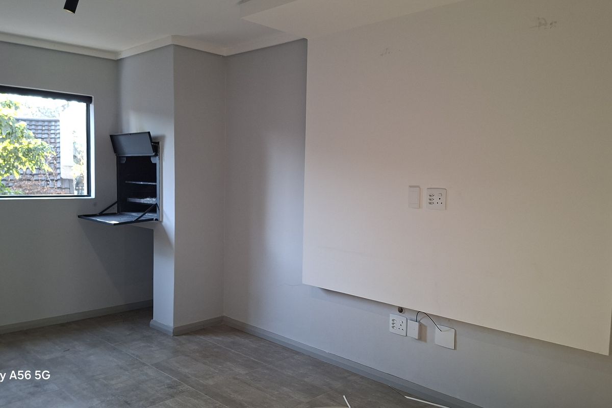 An empty living room featuring tiled flooring, a built-in wall unit, and neutral grey walls, providing a clean canvas for interior design.
