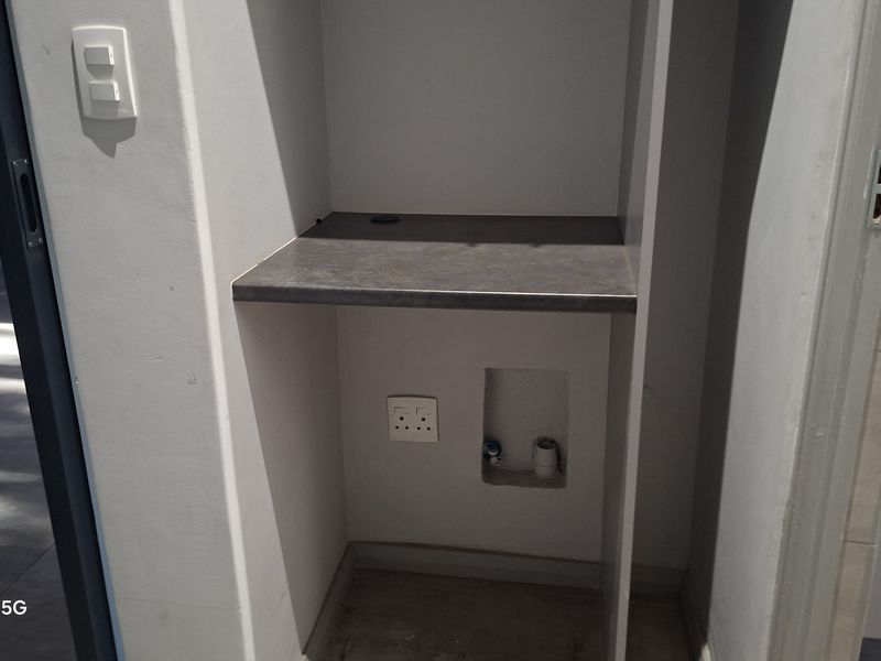 A dedicated laundry nook featuring a built-in countertop with integrated plumbing and electrical connections for a washing machine.