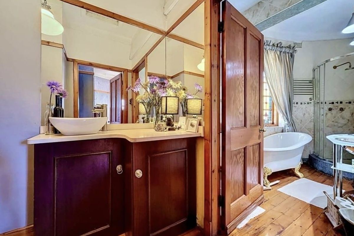 A characterful bathroom featuring a timber vanity with vessel sink, a classic clawfoot bathtub, and a separate corner shower enclosure with timber flooring.