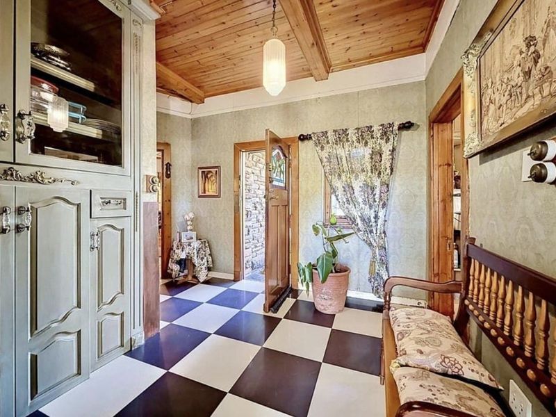 Welcoming entrance hall featuring a distinctive checkered tile floor, timber ceiling beams, and built-in cabinetry, providing a classic and character-filled transition into the home.