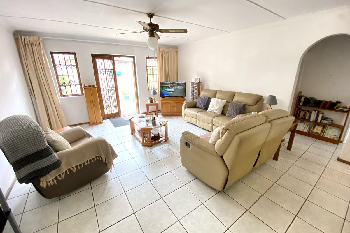 A spacious living room featuring tiled flooring, a ceiling fan, and an arched entryway, with direct access to an outdoor area through a sliding door.