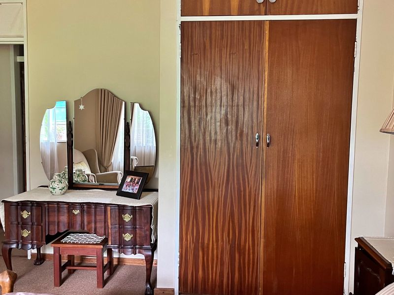 A bedroom featuring a classic built-in wooden wardrobe with overhead storage compartments.