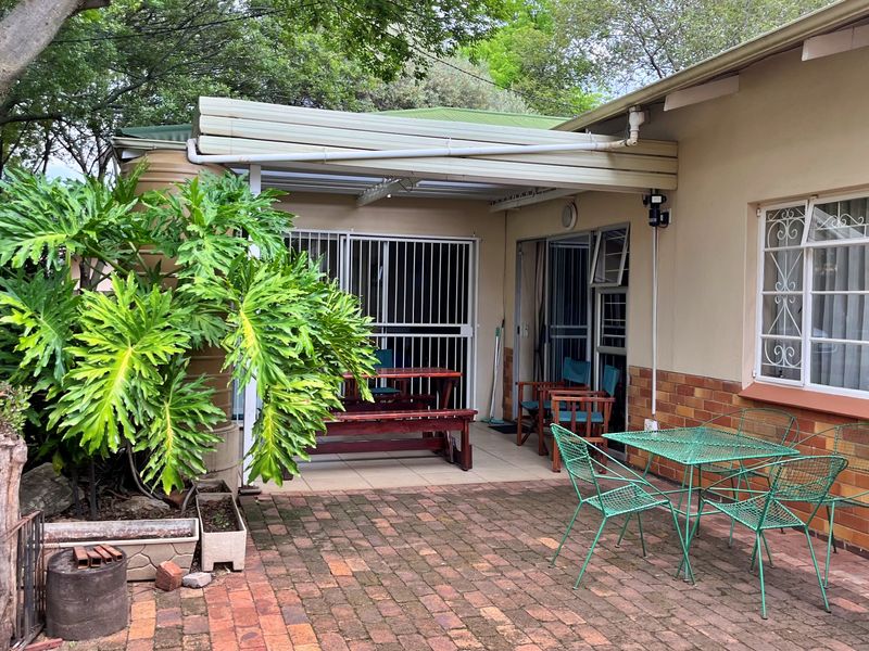 A covered outdoor patio area featuring brick paving, security gates, and direct access to the home, providing a functional space for outdoor relaxation.