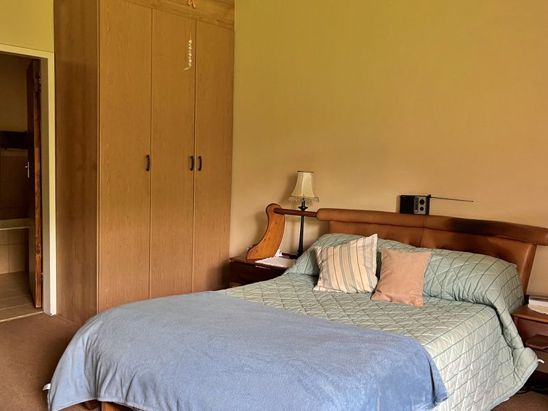 A bedroom featuring a built-in wooden wardrobe and direct access to an en-suite bathroom.