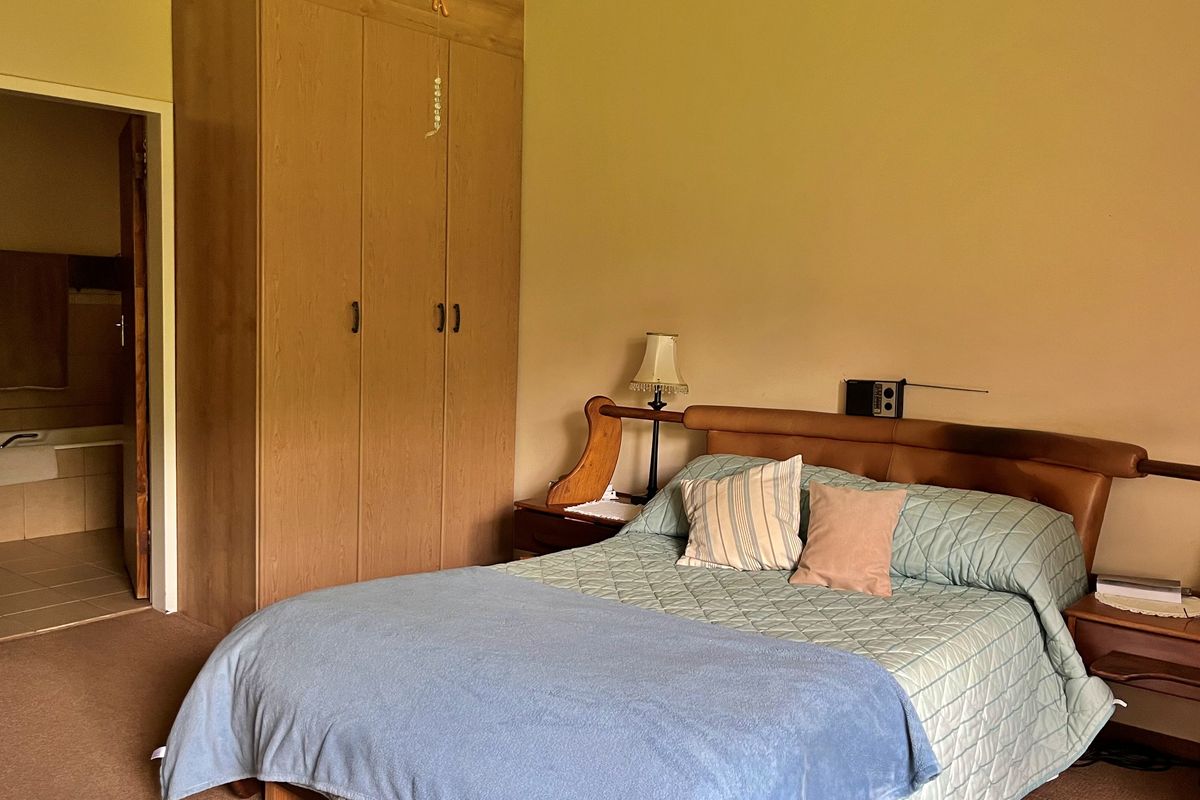 A bedroom featuring a built-in wooden wardrobe and direct access to an en-suite bathroom.