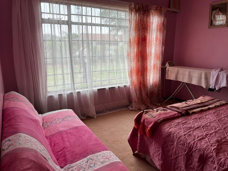 A bedroom featuring a large window with natural light and carpeted flooring.