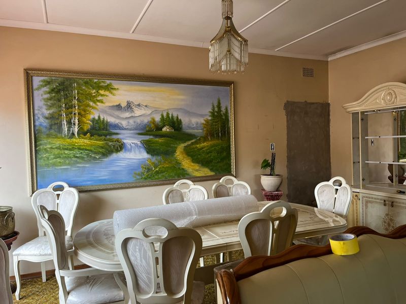 Dining room featuring a crystal chandelier and built-in display cabinet, currently requiring wall repairs and cosmetic updates to improve the space.