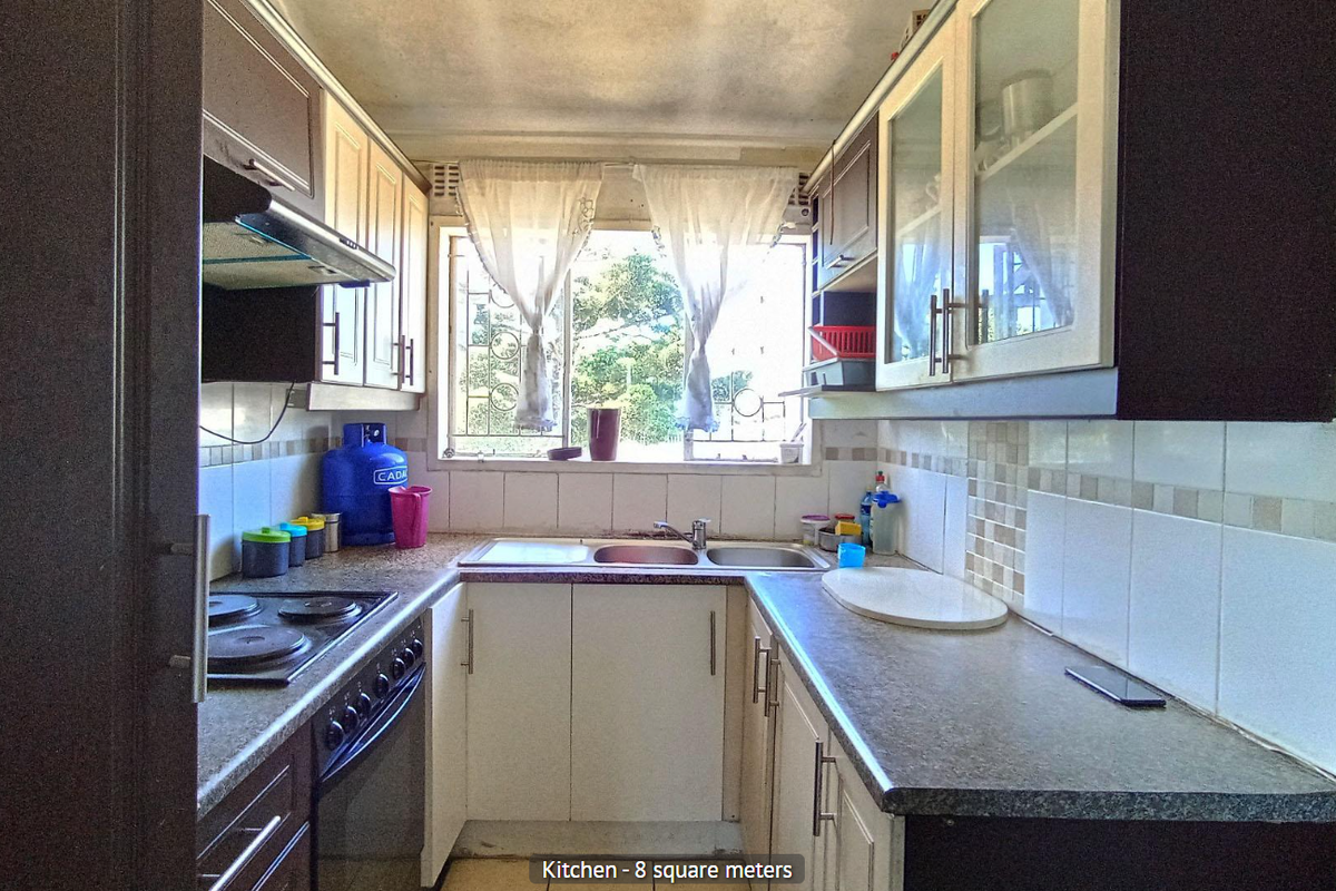 Compact kitchen featuring built-in cabinetry, laminate countertops, a stainless steel double sink, and an integrated electric hob and oven.