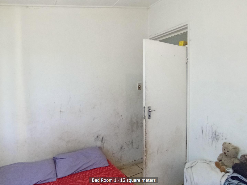 A bedroom featuring plain walls with significant scuffing and wear, requiring cosmetic attention and repainting to restore the space.