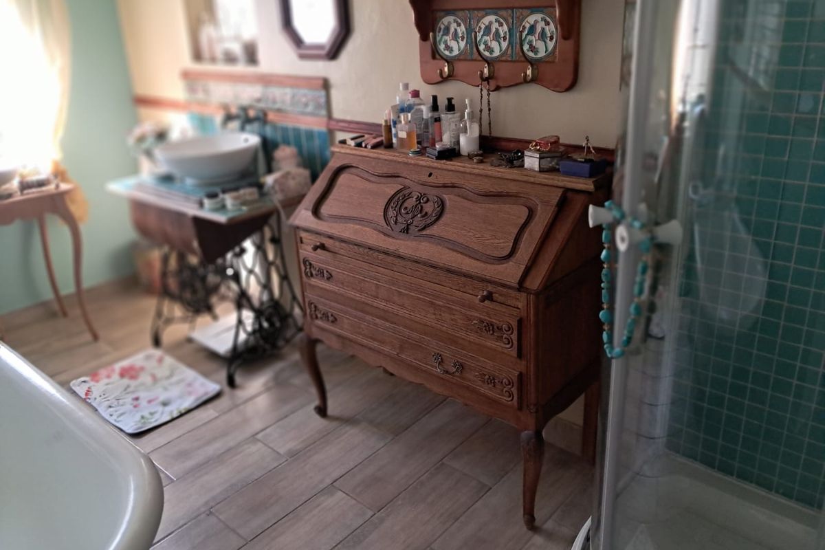 A bathroom featuring a vessel sink, a shower enclosure with tiled walls, and wood-look floor tiles, offering a unique vintage aesthetic.