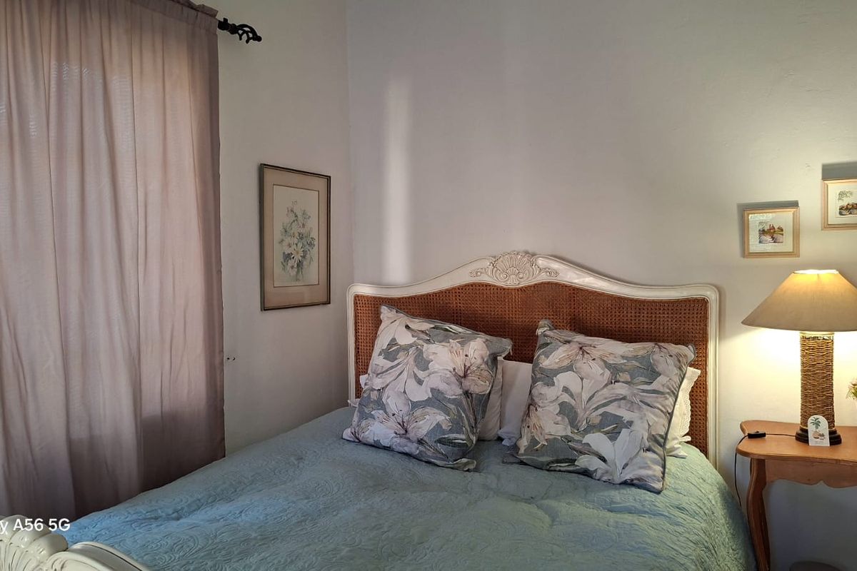 A cozy bedroom featuring neutral wall finishes and natural light through the window.